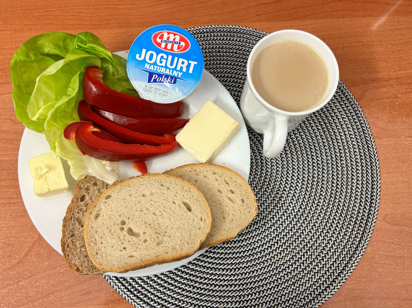 Na zdjęciu znajduje się: Jogurt naturalny, Kawa zbożowa z mlekiem, Chleb mieszany pszenno-żytni, Chleb Graham, Masło extra 82%, Ser topiony, Papryka świeża, Sałata zielona